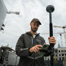 A surveyor setting up an Emlid RS4 GNSS receiver at a construction site
