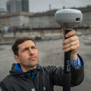 A surveyor setting up the Emlid RS4 Pro GNSS receiver at a construction project site