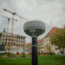 Emlid RS4 GNSS receiver on a survey pole in front of a construction project site