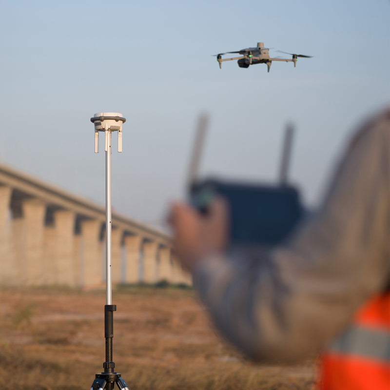 A surveyor flying a Matrice 4 drone while using a DJI D RTK 3 Multifunctional Station for corrections