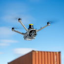 DJI Matrice 4D with an AVSS PRS System flying in an industrial area with storage containers