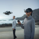Woman flying the DJI Avata 2 while wearing the DJI Goggles 3 and using the DJI RC Motion 2 on a beach